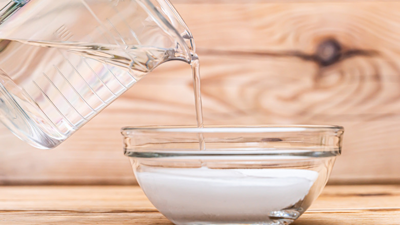 pouring water into white sugar for hummingbird feeder