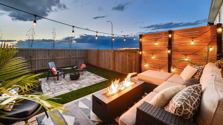 A beautiful patio with warm lights, corner sofa and a fire