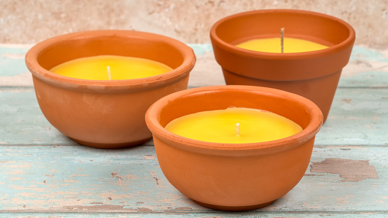 Citronella candles in clay pots on wood table