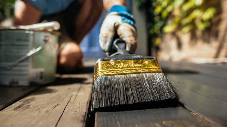 Close up of man oiling deck boards with a brush