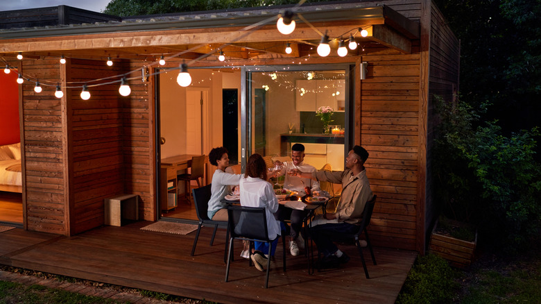Group of friends enjoying a toast on their cozily lit deck