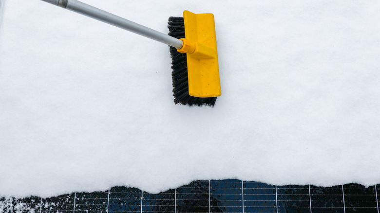 Person brushing snow off a solar panel