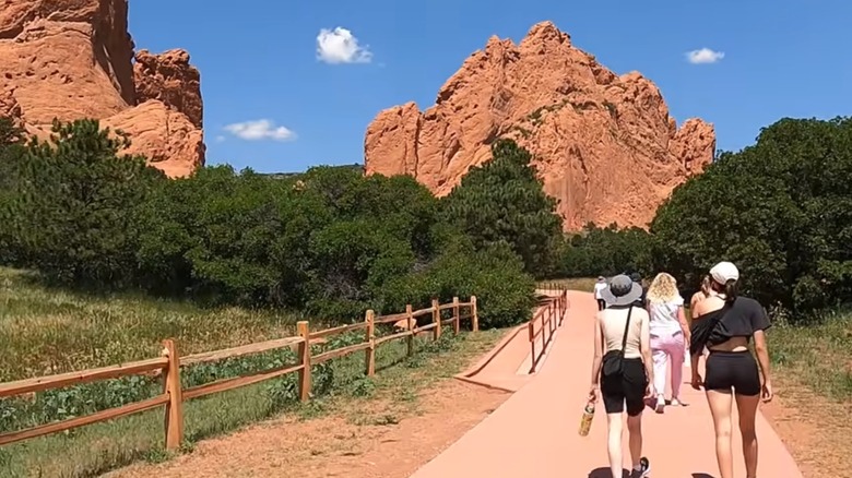 Hikers follow the Central Garden Trail among red rock cliffs