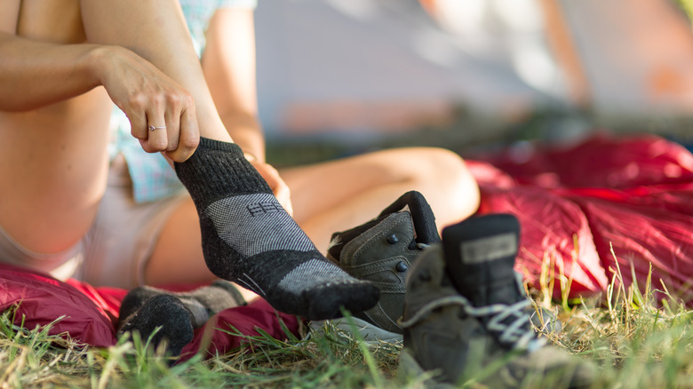 Woman changing socks beside tent