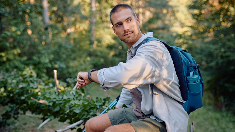 Male hiker checks time while resting
