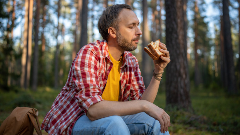Man eats sandwich on hike