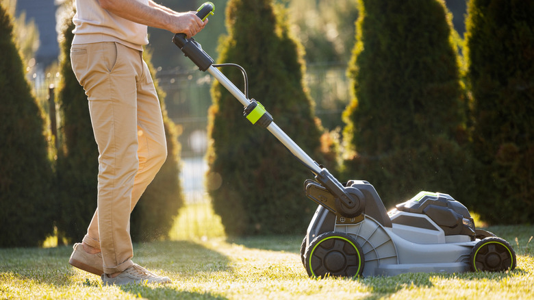 Man pushing electric lawn mower