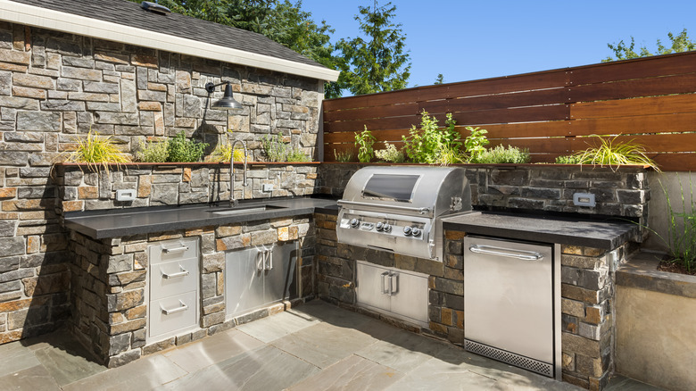 A stone-built outdoor kitchen fitted into a garden corner