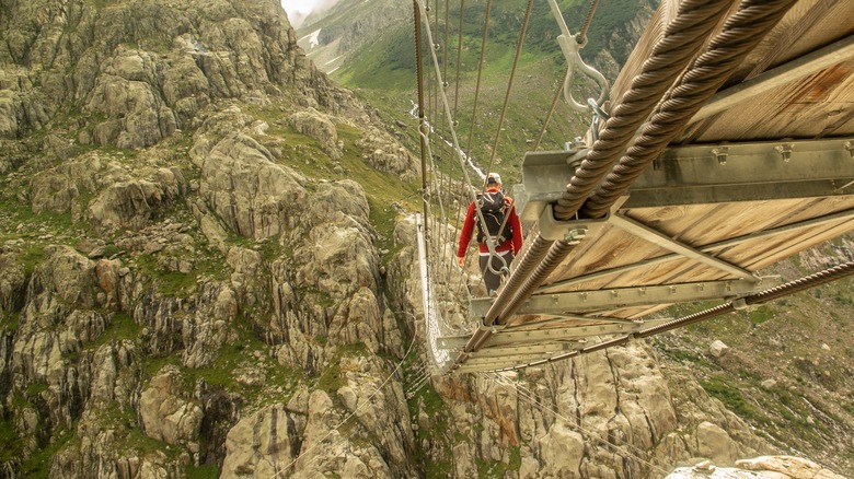 Man walking across Trift bridge in Switzerland