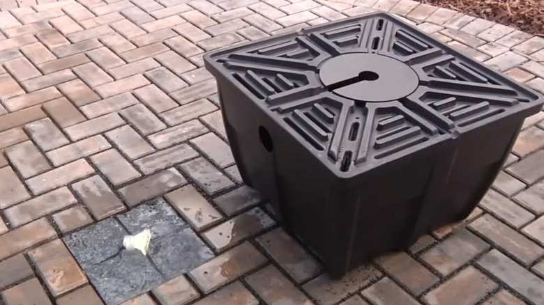 A bubbler water fountain between pavers with the reservoir product next to it.