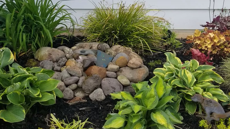 A bubbler fountain in a garden surrounded by rocks