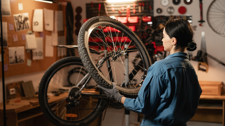 Woman inspecting bicycle wheel in workshop