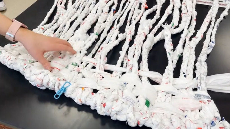Someone making a hammock from braided plastic grocery bags