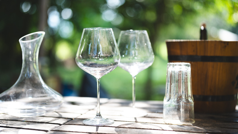wine glasses, a decanter, and water glass on a table outside