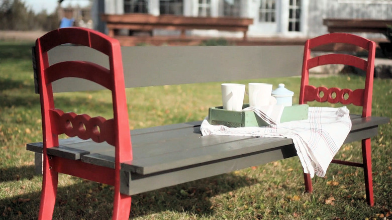 A bench made from two chairs sitting outside in a park