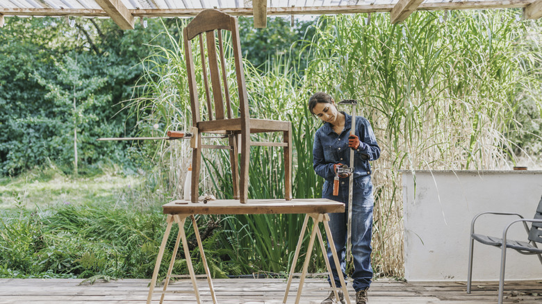 woman taking on a chair DIY project in backyard