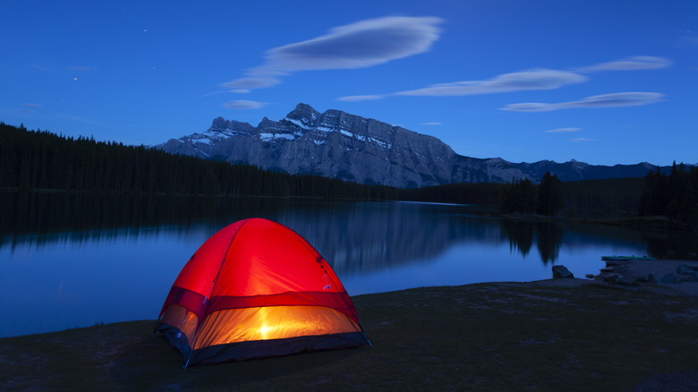 Lakeside tent at night with light inside