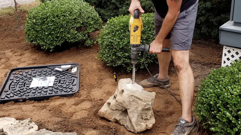 A man drilling holes into a rock to make a fountain