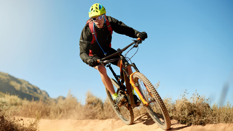 A mountain biker rips through a sandy trail on a beautiful day