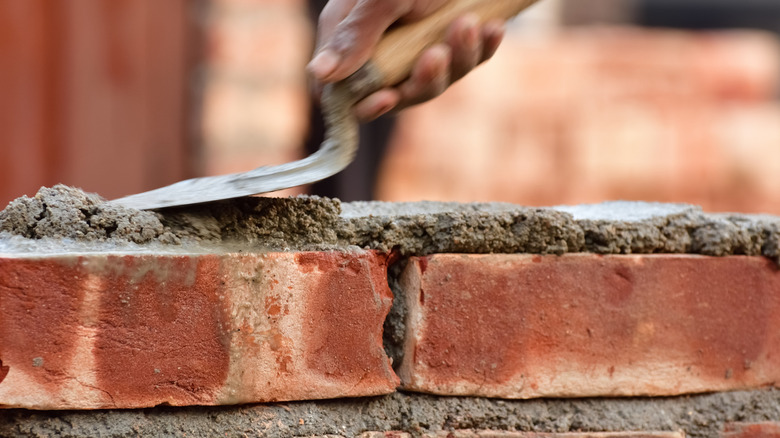 Close-up of a builder laying mortar on a brick wall