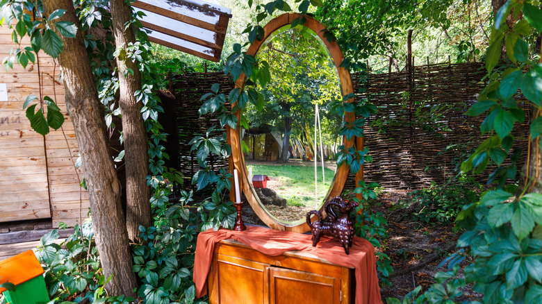 A rustic mirror in a shady corner of a garden