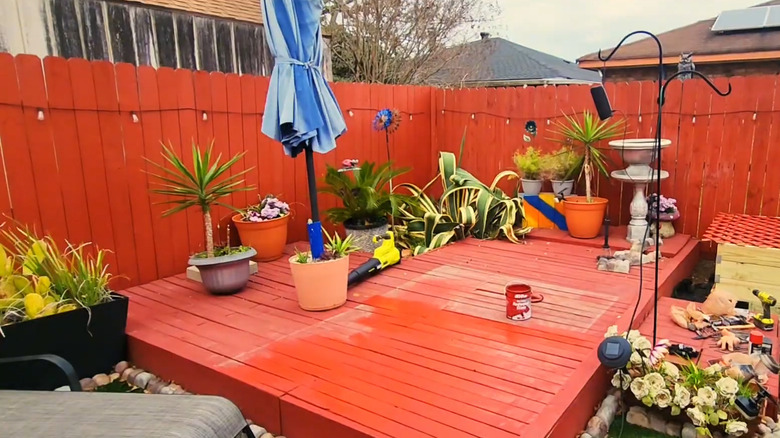 Shanitra Neal's completed pallet deck, painted a terracotta shade, with a blue umbrella and outdoor decor.