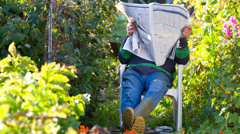 Man reading newspaper in garden