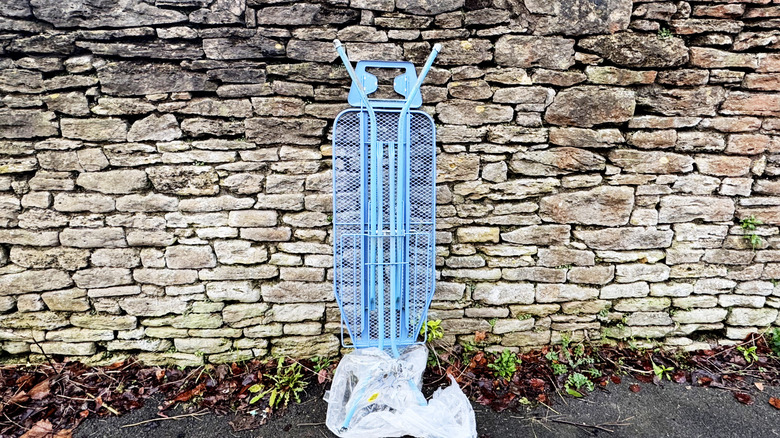 Ironing board leaning against stone wall