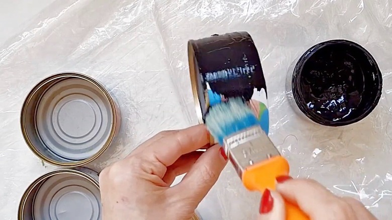Person painting empty tuna cans