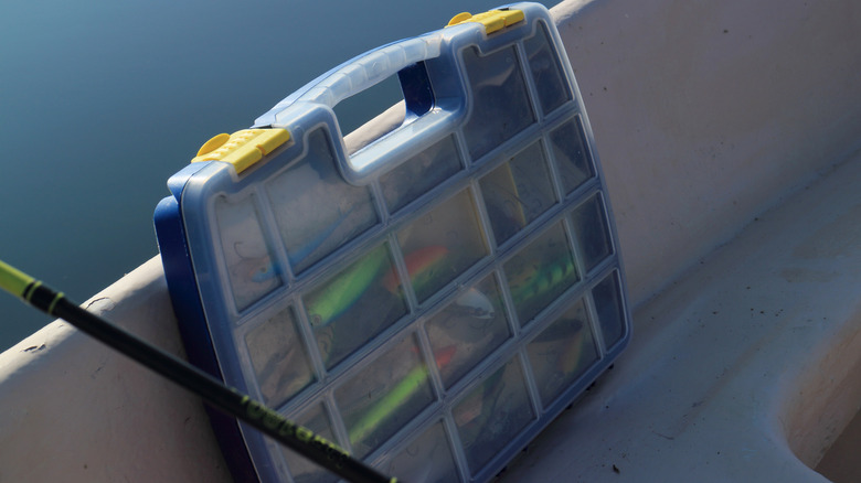 A plastic tackle box with yellow snap tabs containing fishing lures.