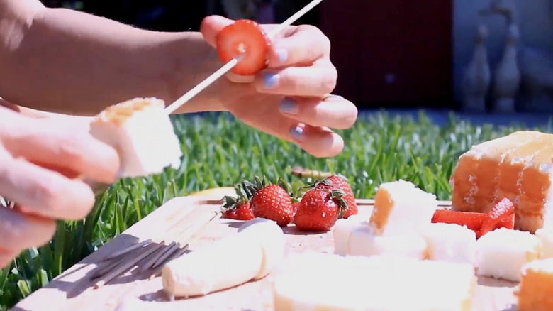 Person making strawberry shortcake kebabs