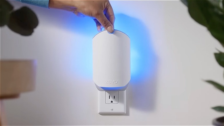 The ZEVO Insect Trap plugged into an outlet emitting visible blue light