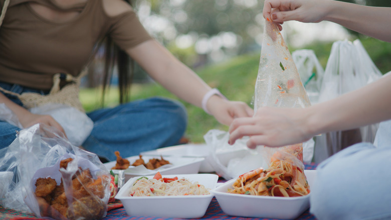 Friends unwrapping plastic from food during camping trip