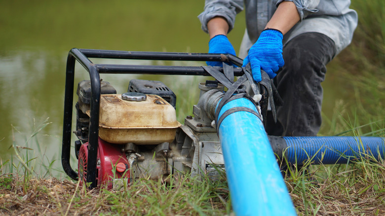 farmer using a submersible pump to remove water from a pond