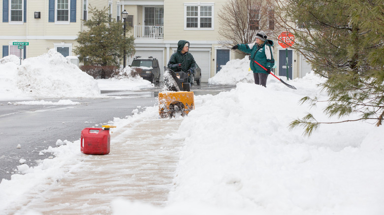 Woman shoveling talks to man with snow blower
