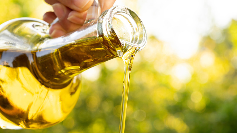 Pouring olive oil from a glass bottle