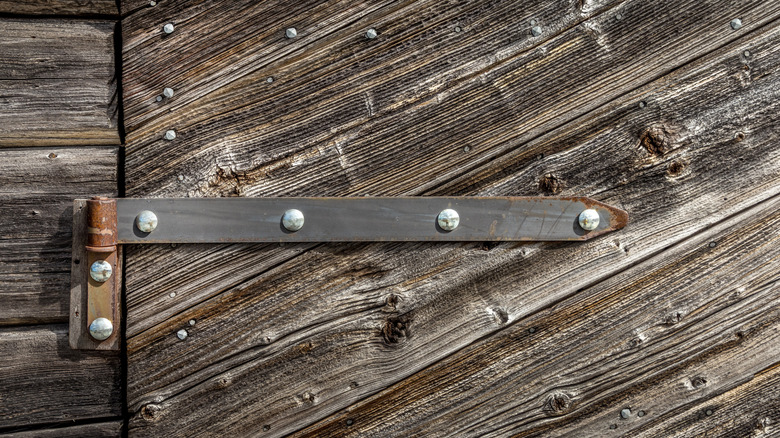 A corroded hinge on a wooden door