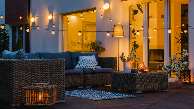 Beautiful, well-lit decking with festoon lights and a floor lamp