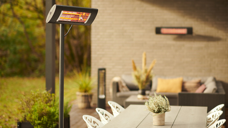 A sheltered outdoor seating area with wall-mounted and standing patio heater