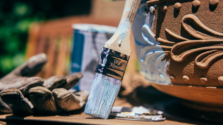 A painting project with a flower pot, paint brush, and paint can