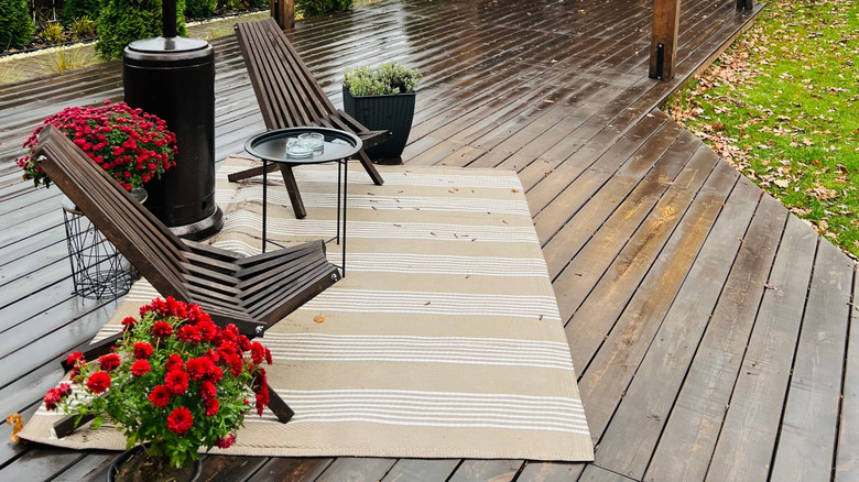 A small, striped outdoor rug on a wooden deck