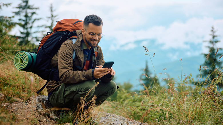 Man hiking with camping supplies and phone
