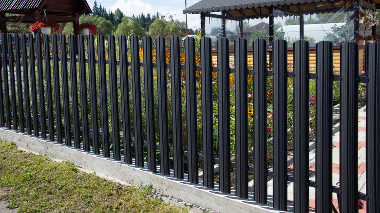 A black aluminum fence in front of a garden