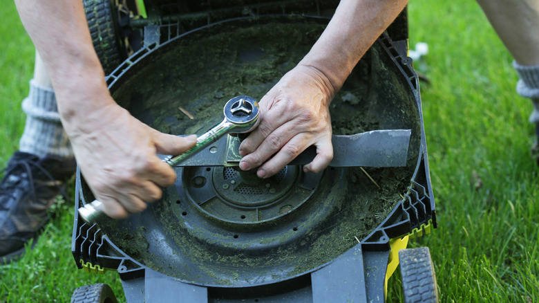 Using a ratchet to adjust or replace lawn mower blades