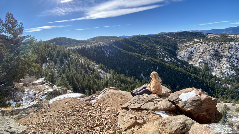A woman sit on a rocky outcrop in Mt. Falcon Park, Colorado