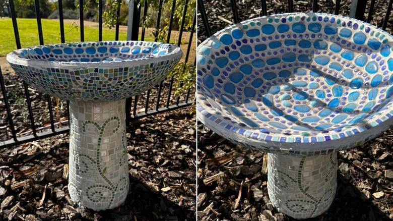 A concrete birdbath covered in mosaic tiles and glass pebbles