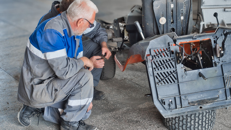 Mechanics repairing rider mower