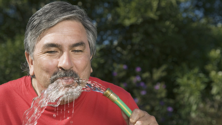 Man drinking from water hose