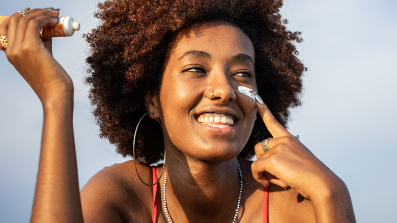 Happy woman applies sunscreen