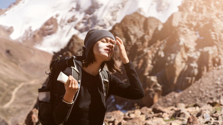 Mountain climber applies sunscreen